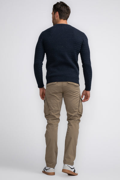Pantalon cargo beige de Petrol Industries, avec poches latérales et bas de survêtement, porté avec un pull bleu marine.