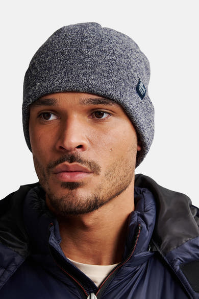 Bonnet bleu chiné de Petrol Industries, porté par un homme avec une doudoune bleu marine.