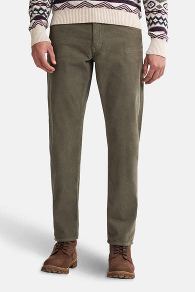 Pantalon vert en velours côtelé par Petrol Industries, porté avec un pull à motifs hivernaux et des bottines en cuir.