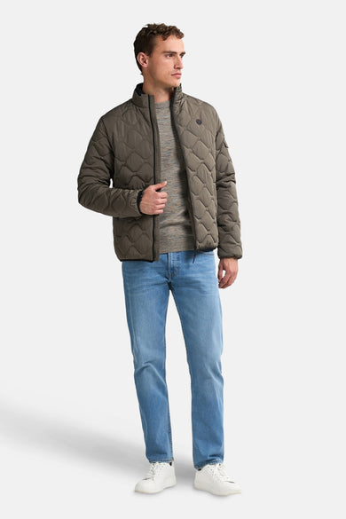 Korte grijze jas van Petrol Industries, doorgestikt patroon, gedragen met een trui en een lichtblauwe jeans.