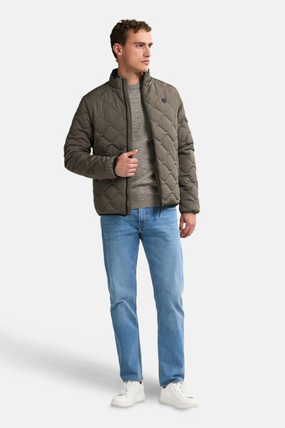 Korte grijze jas van Petrol Industries, doorgestikt patroon, gedragen met een trui en een lichtblauwe jeans.