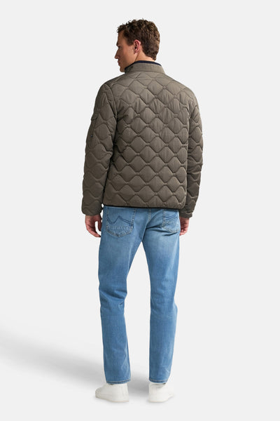 Korte grijze jas van Petrol Industries, met ruitvormig doorgestikt patroon, gedragen met een blauwe jeans en witte schoenen.