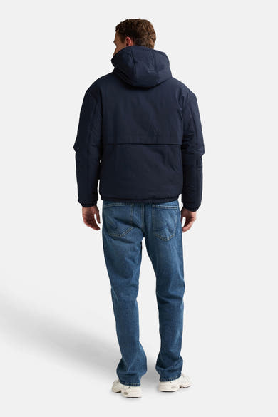 Veste courte bleue de Petrol Industries®, avec capuche, vue de dos, portée avec un jean et des chaussures de sport blanches