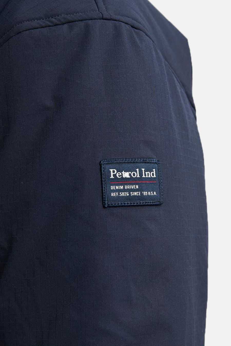 Veste courte bleue de Petrol Industries, avec un motif quadrillé subtil et un écusson de la marque.
