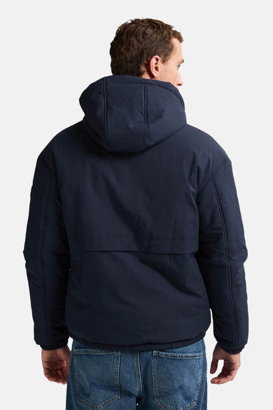 Veste courte bleue par Petrol Industries, avec capuche et coupe décontractée, portée avec un jean visible de dos.