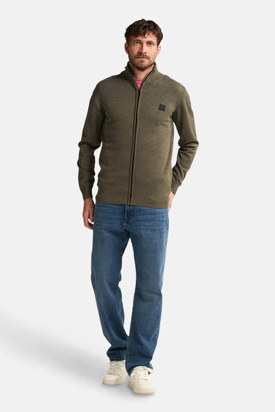 Groen gilet van Petrol Industries, gedragen met een roze T-shirt, een blauwe jeans en witte sneakers.