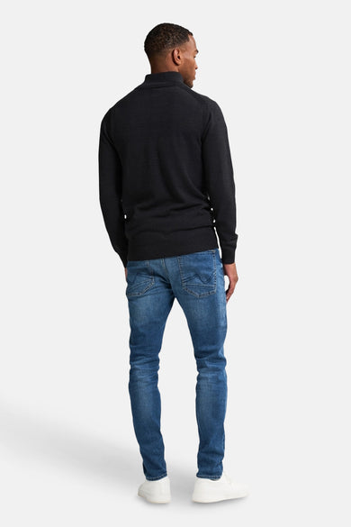 Zwarte bodywarmer van Petrol Industries, gedragen met een blauwe jeans en witte schoenen, achtergezicht.