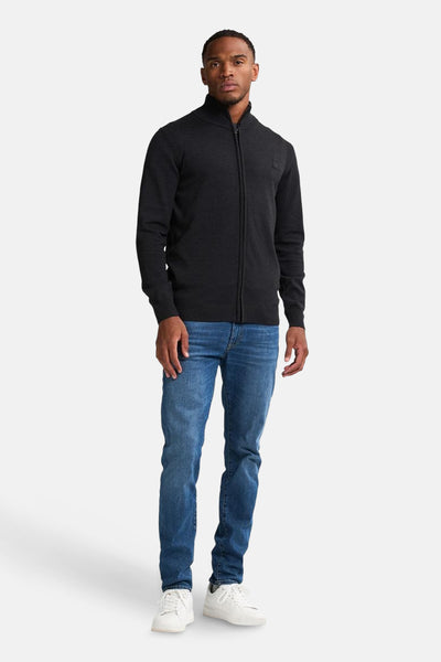 Gilet noir zippé de Petrol Industries, porté avec un jean bleu et des baskets blanches.