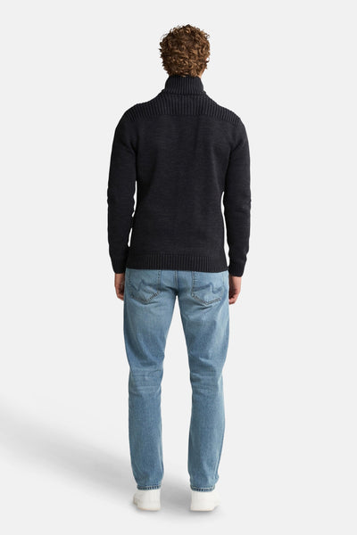 Zwarte bodywarmer van Petrol Industries, gedragen met een blauwe jeans en witte sneakers.
