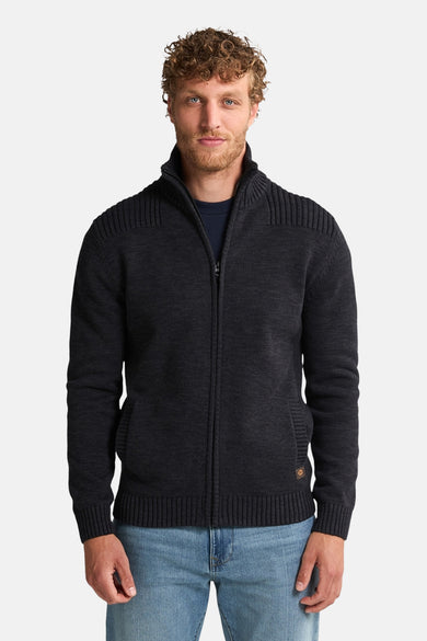 Zwart gewatteerd vest met rits van Petrol Industries, met textuur op de schouders en voorzakken, gedragen over een marineblauw T-shirt en een blauwe jeans.