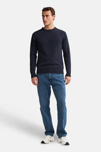 Ronde hals trui blauw van Petrol Industries, gedragen met een blauwe jeans en witte sneakers.