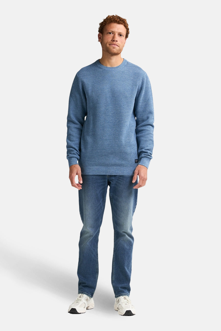 Ronde hals trui blauw van Petrol Industries, gedragen met een spijkerbroek en witte sneakers.