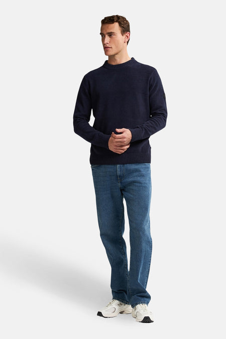 Ronde hals trui blauw van Petrol Industries®, gedragen met een blauwe spijkerbroek en witte sneakers.