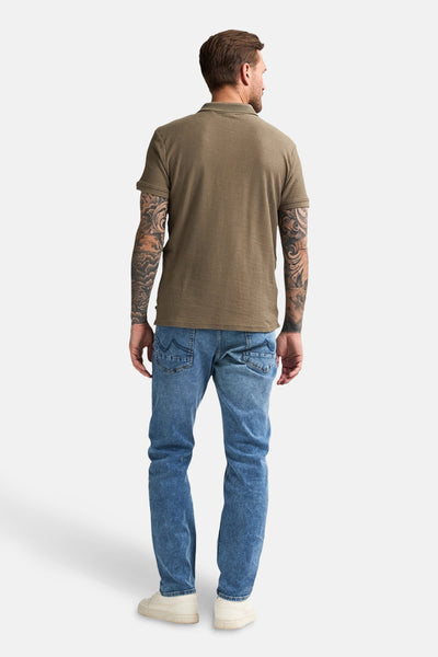 Polo à manches courtes vert de Petrol Industries, porté avec un jean et des baskets, vu de dos.
