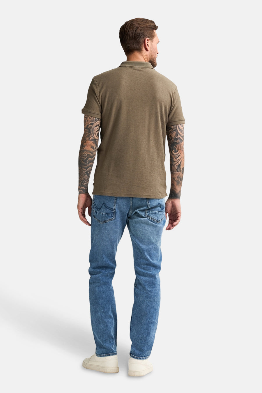 Groen poloshirt met korte mouwen van Petrol Industries, gedragen met een spijkerbroek en sneakers, van achteren gezien.