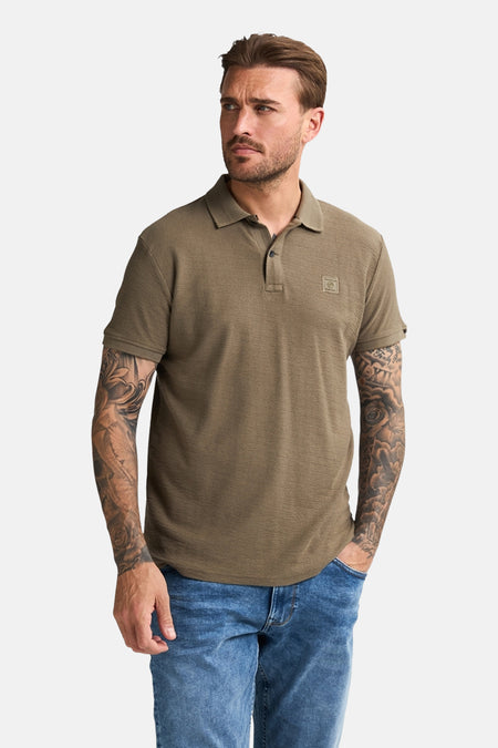 Groen poloshirt met korte mouwen van Petrol Industries, met wafelstructuur, gedragen met een blauwe jeans.