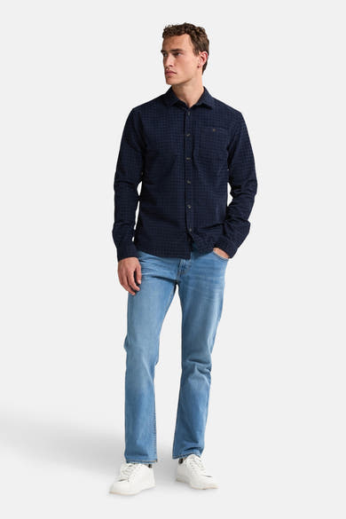 Blauw overhemd met lange mouwen van Petrol Industries, geruit, gedragen met een lichte spijkerbroek en witte sneakers.