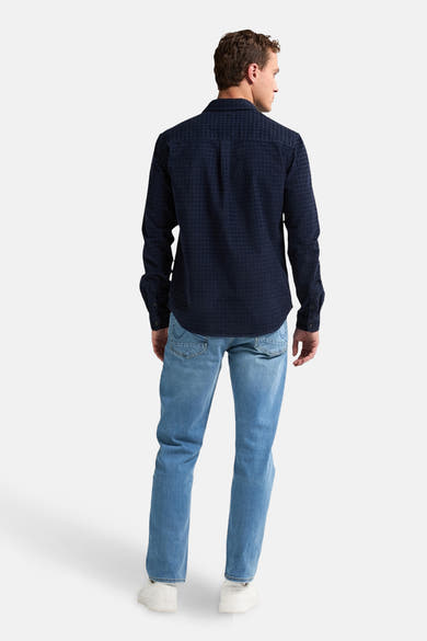 Blauw overhemd met lange mouwen van Petrol Industries, subtiel geruit patroon, gedragen met een lichte spijkerbroek en witte sneakers.