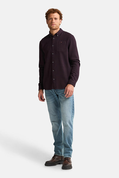 Bordeaux overhemd met lange mouwen van Petrol Industries, met een borstzak en gedragen met een blauwe jeans en bruine schoenen.