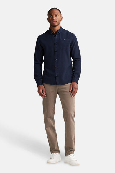 Chemise à manches longues bleue de Petrol Industries, avec poche poitrine et boutons apparents, portée avec un pantalon marron.