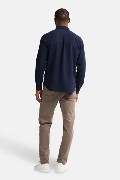 Chemise à manches longues bleue de Petrol Industries®, vue de dos, portée avec un pantalon marron clair et des chaussures blanches.
