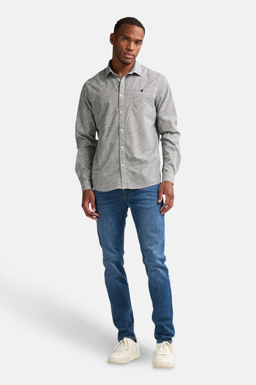 Groen overhemd met lange mouwen van Petrol Industries, met een subtiel patroon, gedragen met een blauwe jeans en witte sneakers.