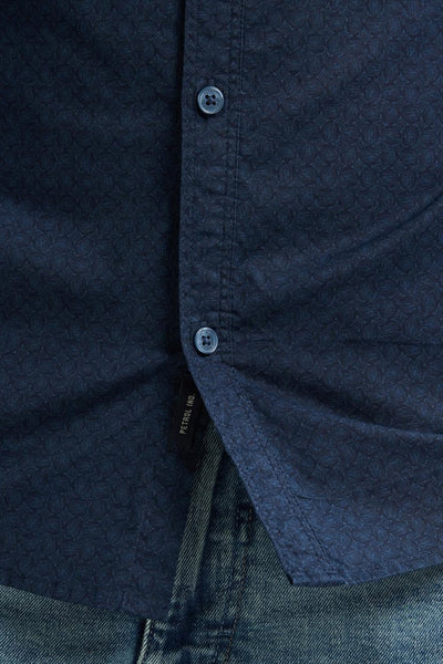 Chemise à manches longues bleue de Petrol Industries avec motif subtil et boutons apparents, portée avec un jean.