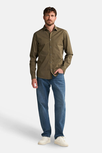 Groen overhemd met lange mouwen van Petrol Industries, met een discreet patroon, gedragen met een blauwe jeans en witte sneakers.