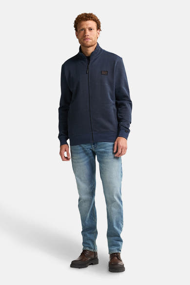 Blauwe bodywarmer van Petrol Industries, met volledige ritssluiting en gedragen met een spijkerbroek en laarzen.