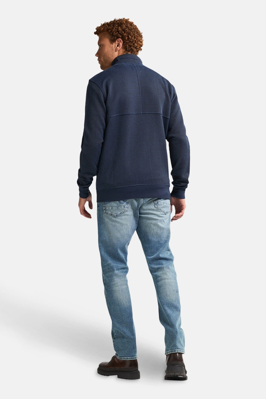 Blauwe bodywarmer van Petrol Industries, gedragen met een verbleekte spijkerbroek en bruine schoenen, achterzicht.