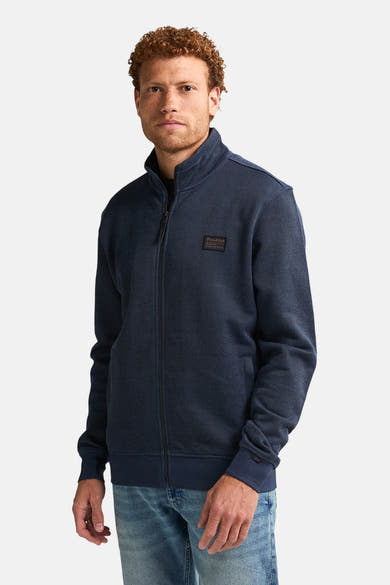 Blauwe bodywarmer van Petrol Industries, met volledige ritssluiting, gedragen met een verbleekte spijkerbroek.