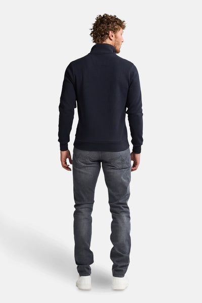 Blauwe sweater met opstaande kraag van Petrol Industries met lange mouwen, gedragen met een grijze jeans en witte sneakers.