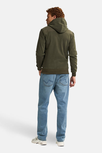 Olijfgroen sweatvest met rits van Petrol Industries, gedragen met een blauwe jeans en witte sneakers, achtergezicht.