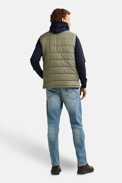 Kaki mouwloos jack van Petrol Industries, gedragen over een marineblauwe hoodie en een blauwe jeans, van achteren gezien.