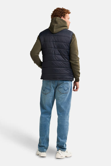 Zwart mouwloos jack van Petrol Industries®, gedragen over een hoodie en een casual spijkerbroek.