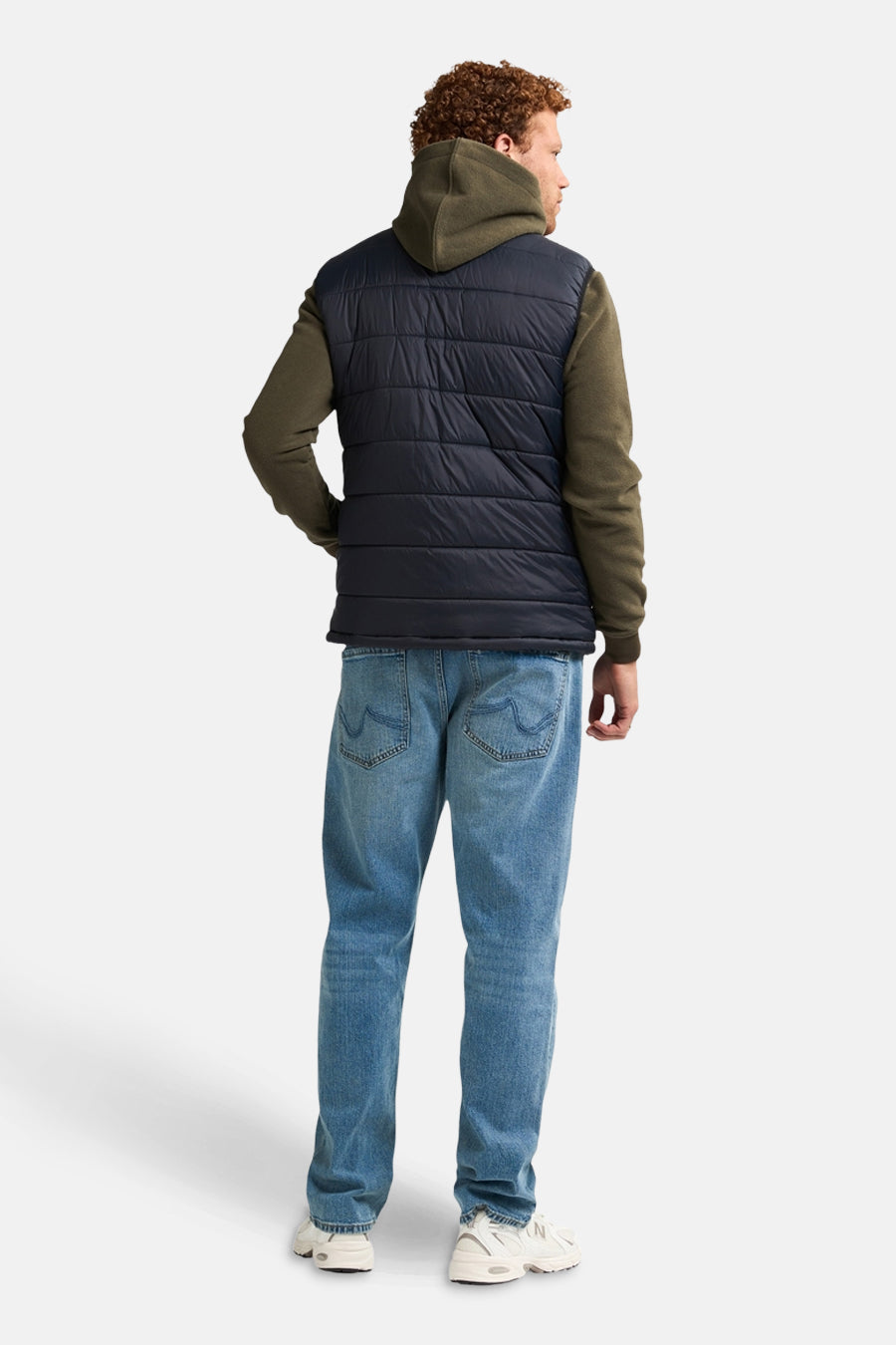 Zwart mouwloos jack van Petrol Industries®, gedragen over een hoodie en een casual spijkerbroek.