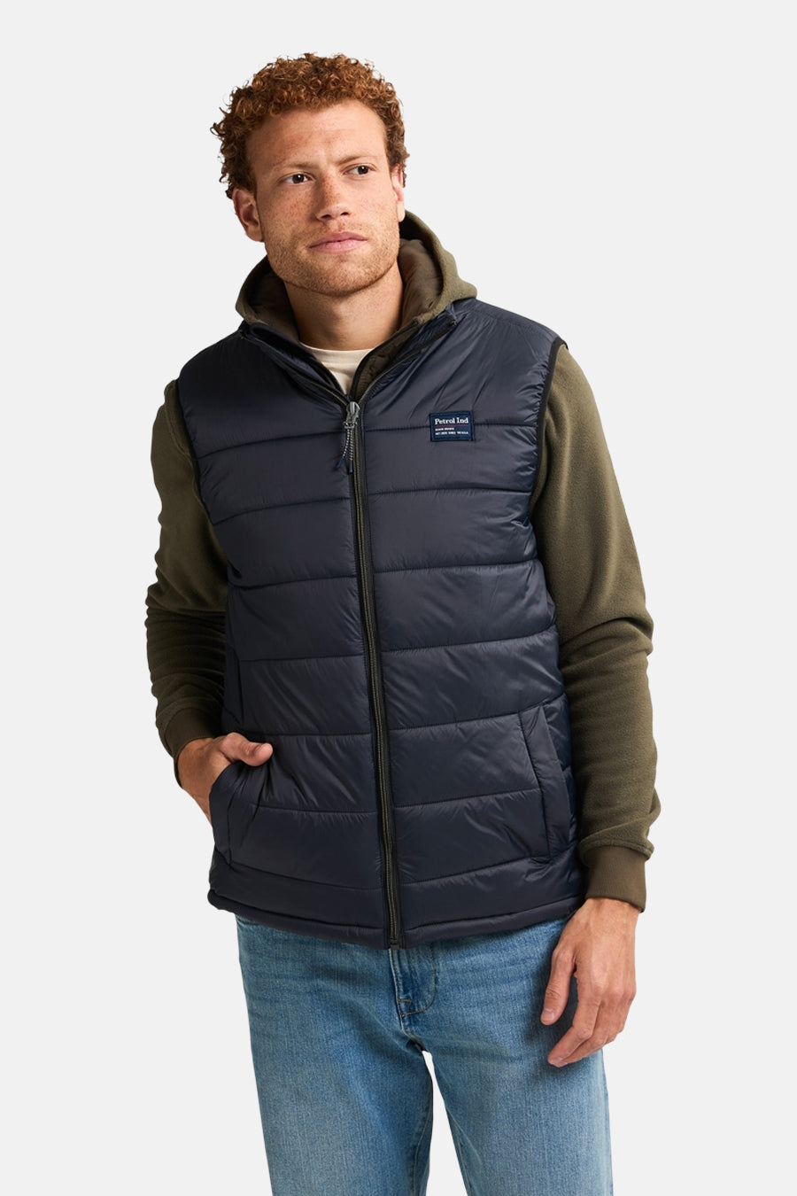 Zwart mouwloos jack van Petrol Industries, gedragen over een olijfgroene hoodie en een blauwe jeans.
