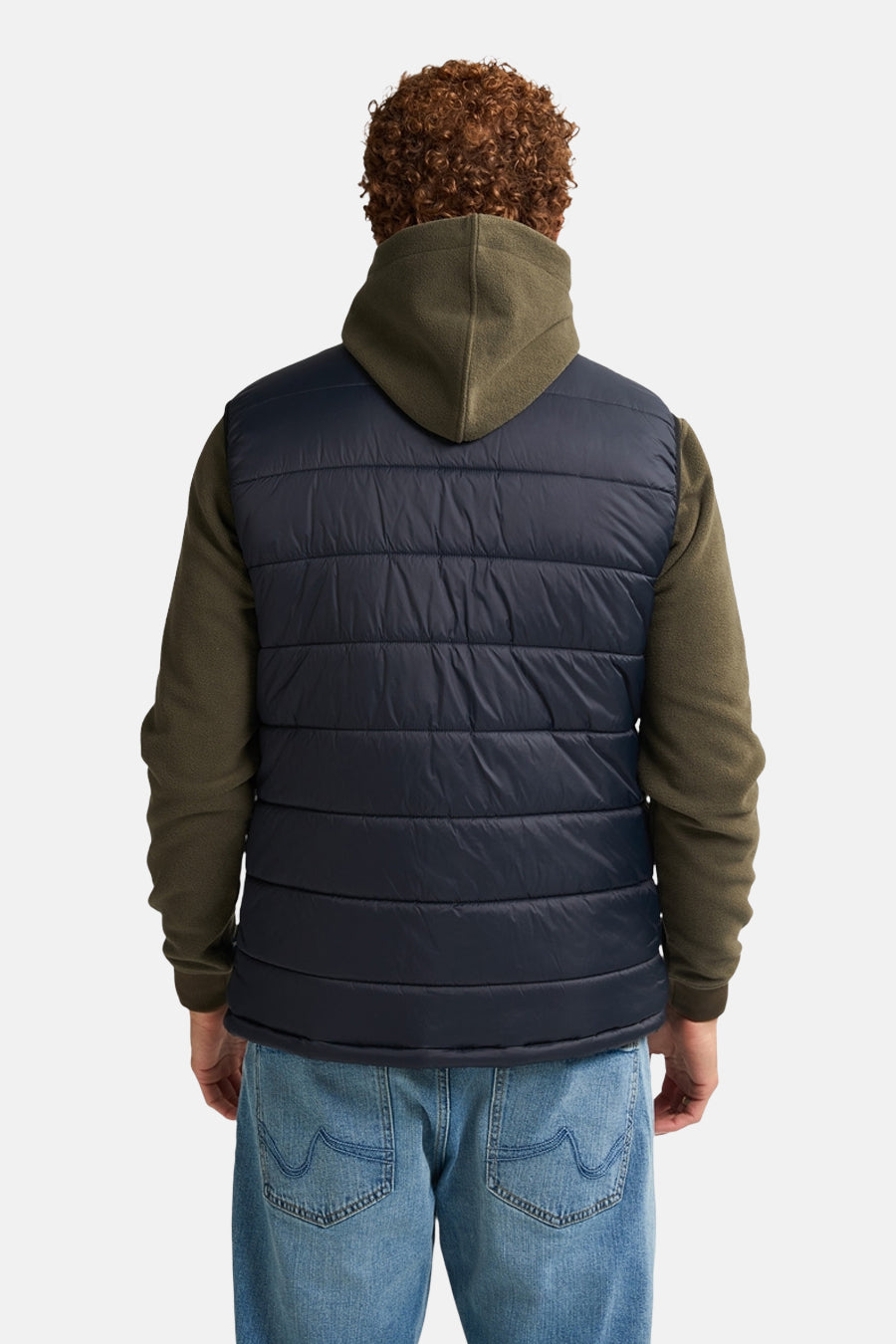 Zwart mouwloos gewatteerd Petrol Industries vest met olijfgroene capuchon, gedragen over een hoodie en een spijkerbroek.