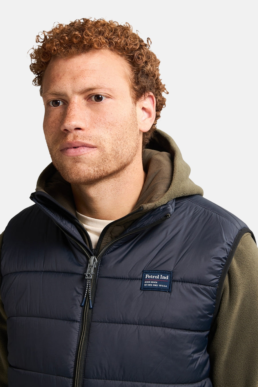 Zwart mouwloos jack van Petrol Industries, gedragen over een olijfgroene hoodie.