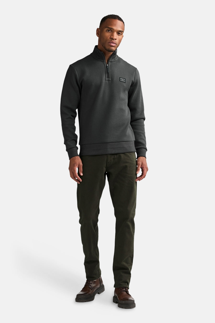 Brown five-pocket seasonal men's trousers by Petrol Industries, worn with dark grey zip-neck sweater and brown boots, full-length front view