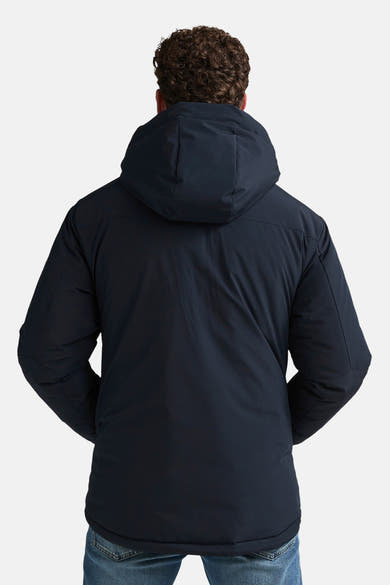 Black long puffer vest with hood, back view, worn over blue jeans, smooth matte finish