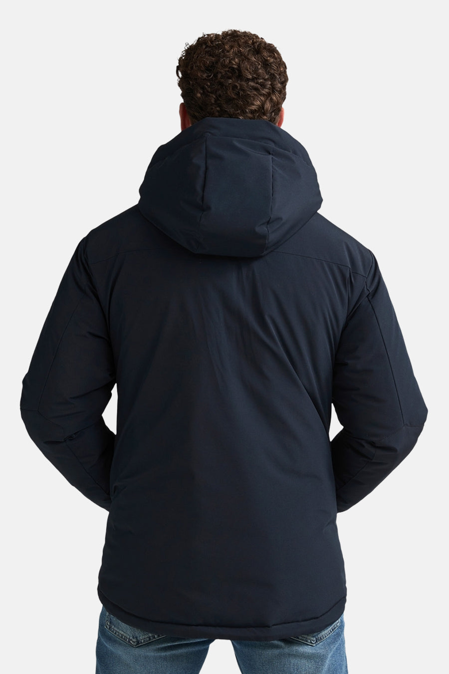 Black long puffer vest with hood, back view, worn over blue jeans, smooth matte finish