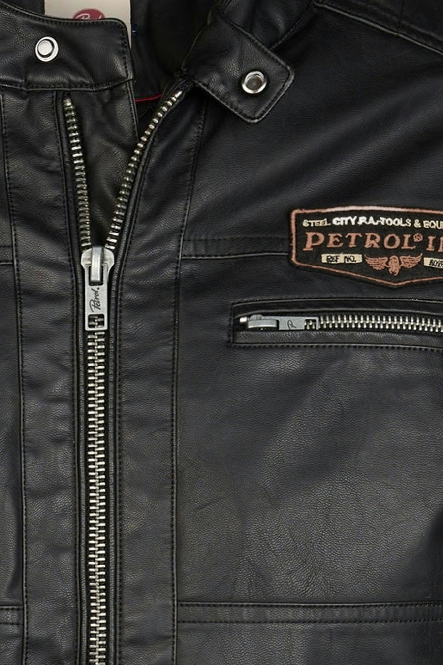 Black denim vest with silver zippers and PETROL patch, close-up front view