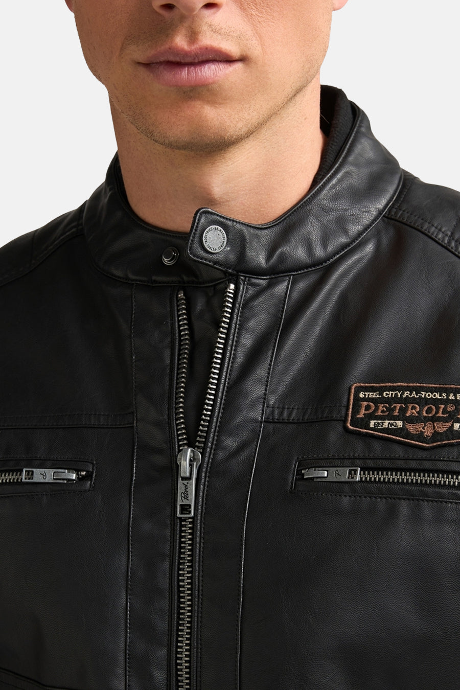 Black denim vest with leather collar and front zipper, featuring patch details and side pockets, close-up front view