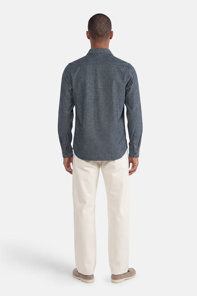 Blue long-sleeve shirt with textured fabric, back view, worn with cream trousers and beige shoes