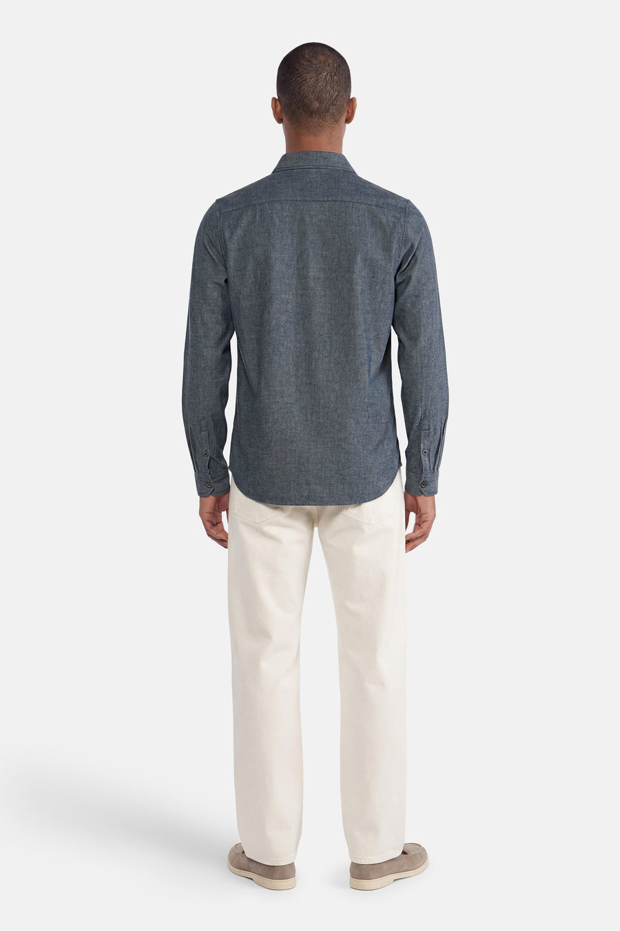 Blue long-sleeve shirt with textured fabric, back view, worn with cream trousers and beige shoes