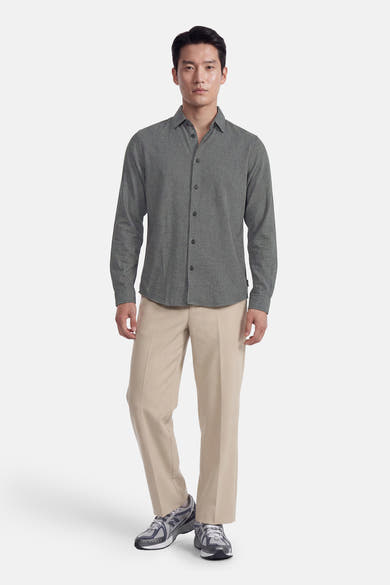 Green long-sleeve shirt with textured fabric and button-down front, worn with beige trousers and gray sneakers, full-body front view.