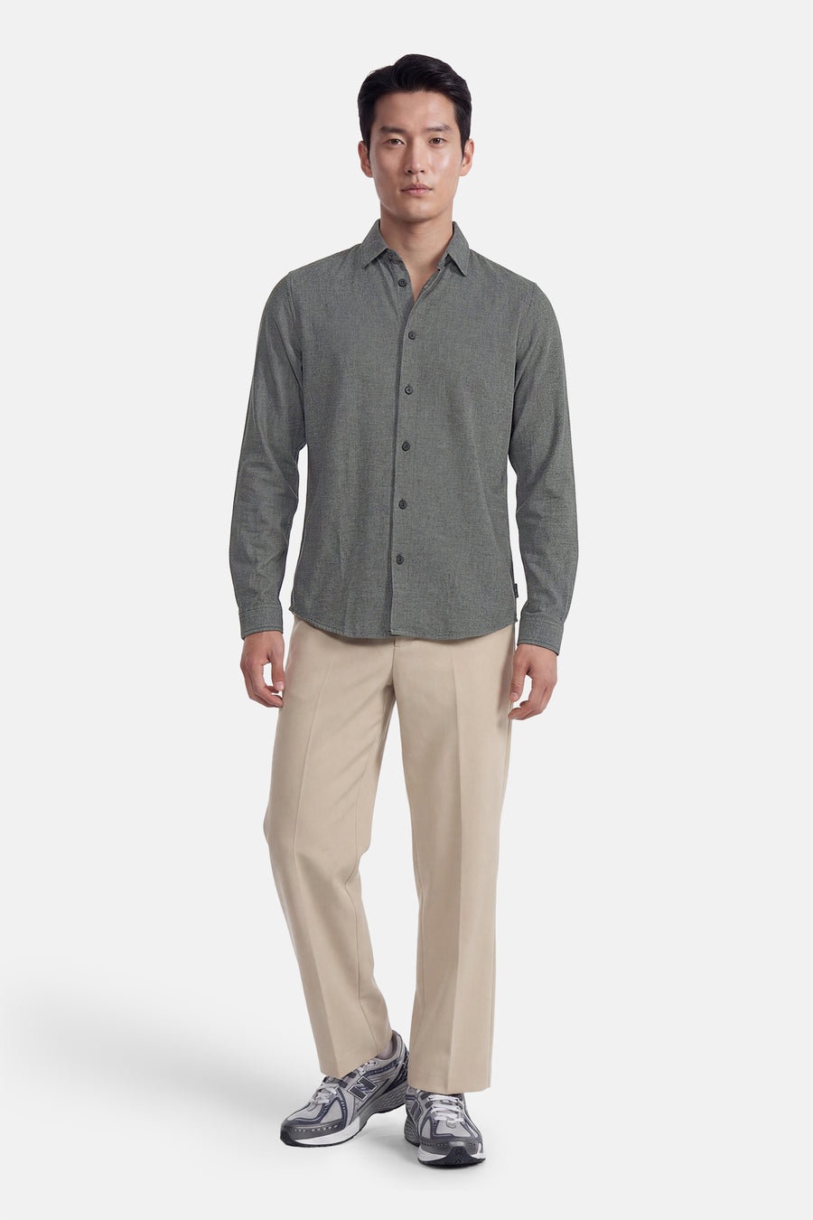 Green long-sleeve shirt with textured fabric and button-down front, worn with beige trousers and gray sneakers, full-body front view.