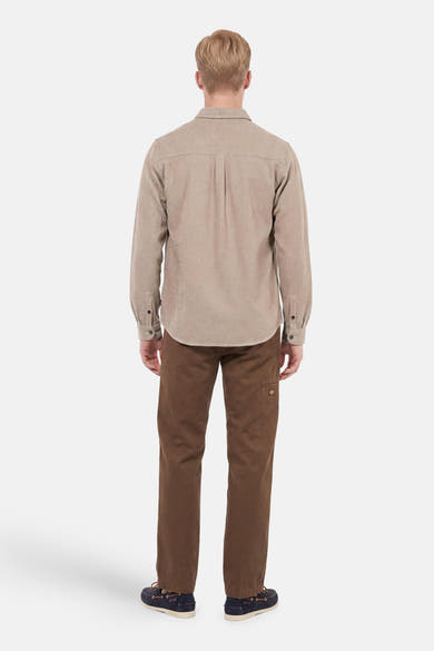 Beige long-sleeve shirt with textured fabric and back pleat, worn by model in back view with brown pants and navy shoes