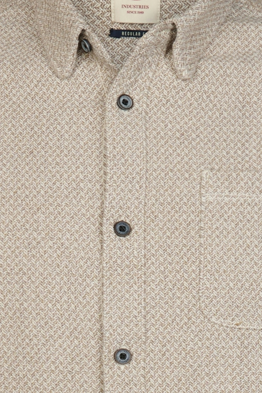 Beige long-sleeve shirt with herringbone texture and chest pocket, by Industries, featuring dark buttons and collar detail, close-up front view